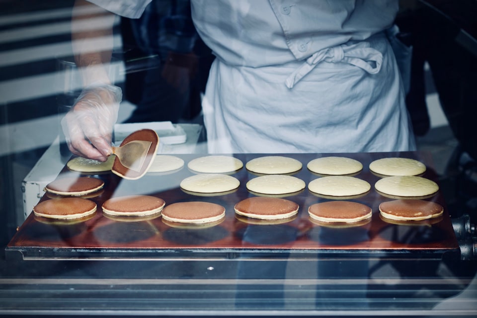 Un cuisinier prépare des hirams plattars suédois à travers une vitrine.