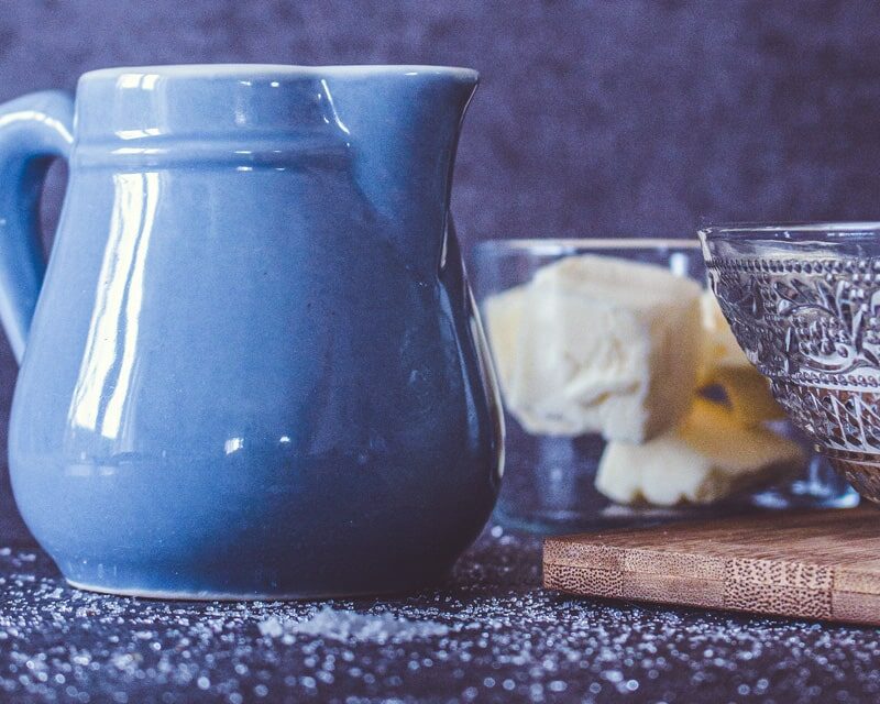 Tellière bleu ciel et verre contenant du beurre salé sur une table de cuisine