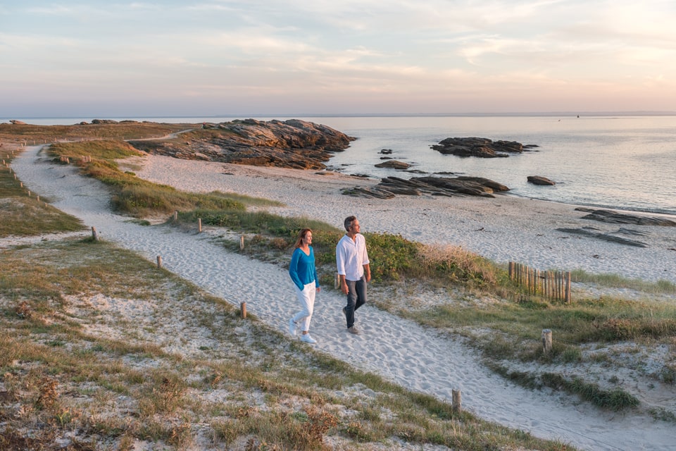 Couple se baladant sur un sentier de sable en bord de mer à Quiberon