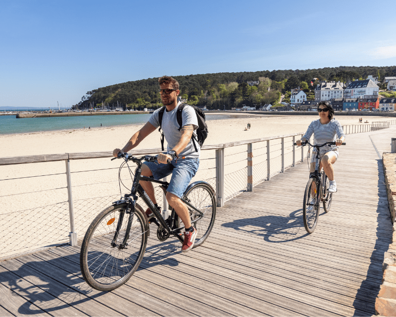 Un couple fait du vélo sur le bord de la plage de Morgat.