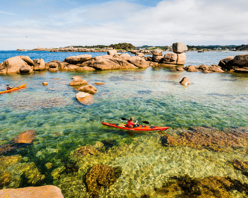 Un homme fait du kayak dans les eaux transparentes des Côtes d'Armor