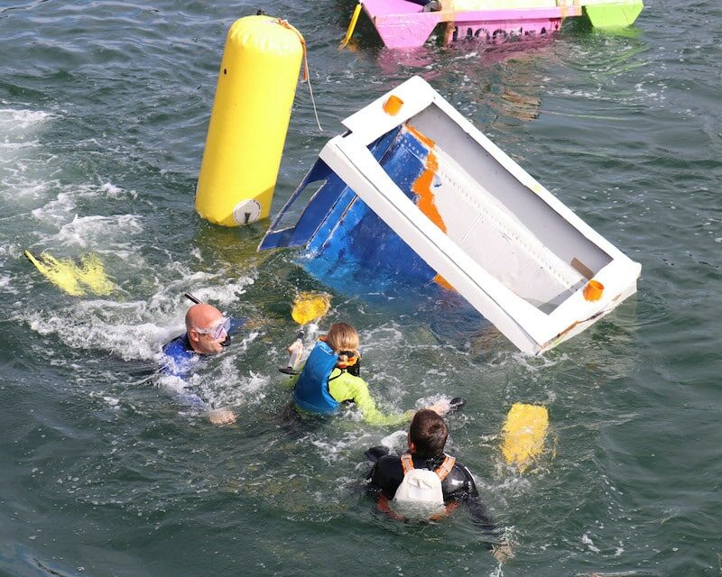 Bateau en carton retourné et équipage à l'eau