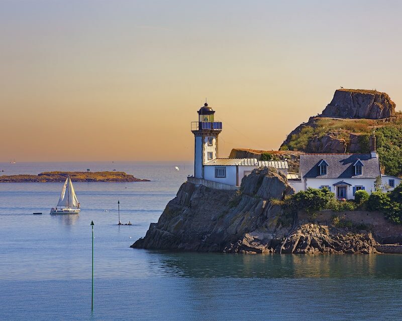 Vue sur un phare et un voilier à l'horizon