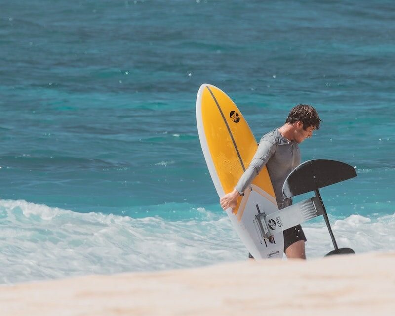 Homme qui sort de l'eau avec une planche de surf foil