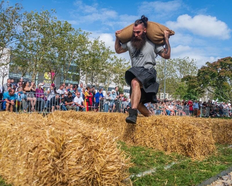 Homme sautant par-dessus une botte de paille